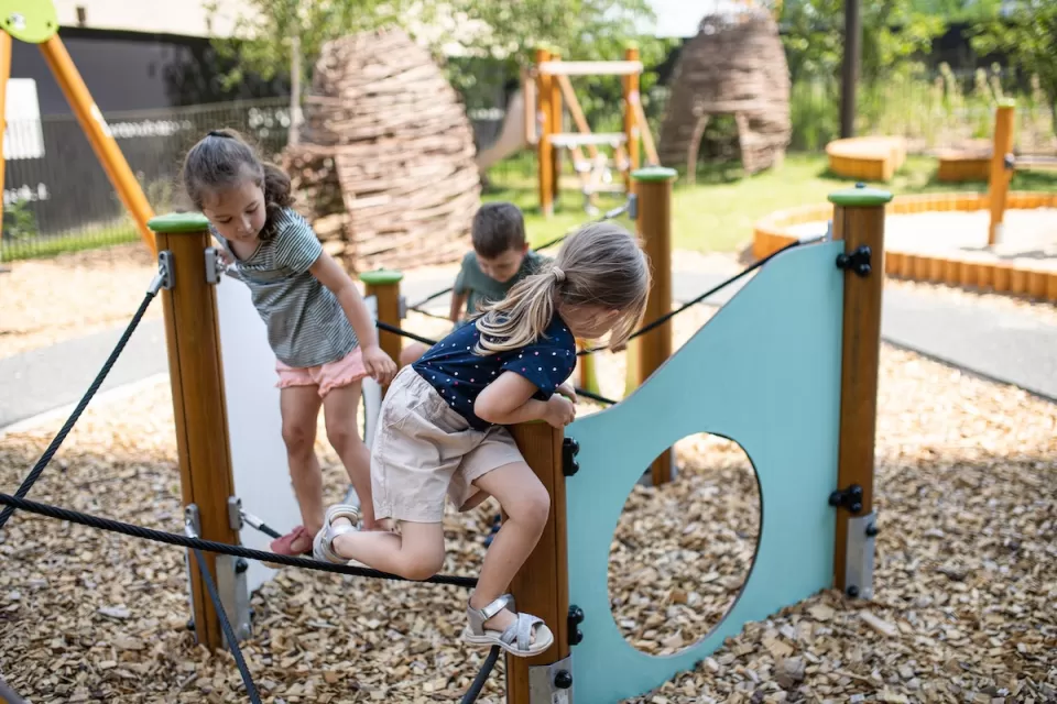 Group of three children playing on playground equipment.